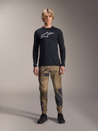 Alpinestars A-Dura Astar Long Sleeve Jersey, Black, featuring a large white Astars logo on the chest, worn with camouflage pants and black shoes, casual mountain bike performance wear