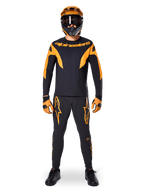 MTB rider wearing Alpinestars A-Supra Race Jersey - Long Sleeve in Black and Orange, matching black and orange pants, gloves, and a full-face helmet with goggles, coordinated mountain bike kit for racing and off-road performance