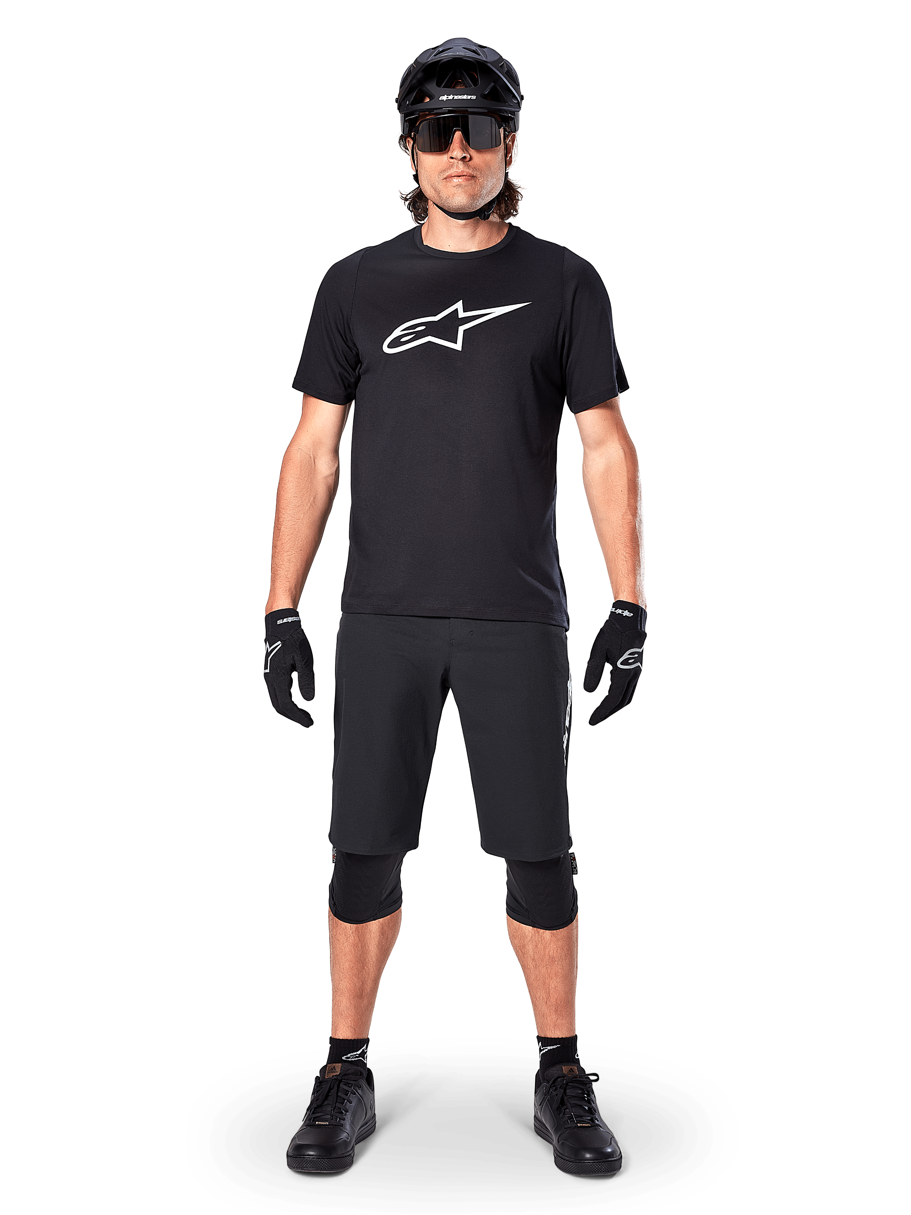 Alpinestars A-Dura Dri Oscar Short Sleeve Jersey, Black Reflective, worn with matching black MTB shorts, gloves, knee pads, and helmet, featuring a large white Alpinestars logo on the chest, complete mountain biking outfit