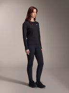 Woman wearing the Alpinestars Stella A-Dura Thermal Jersey, long-sleeve black MTB jersey with white chest logo, styled with matching black pants and athletic shoes, studio portrait for performance cycling apparel