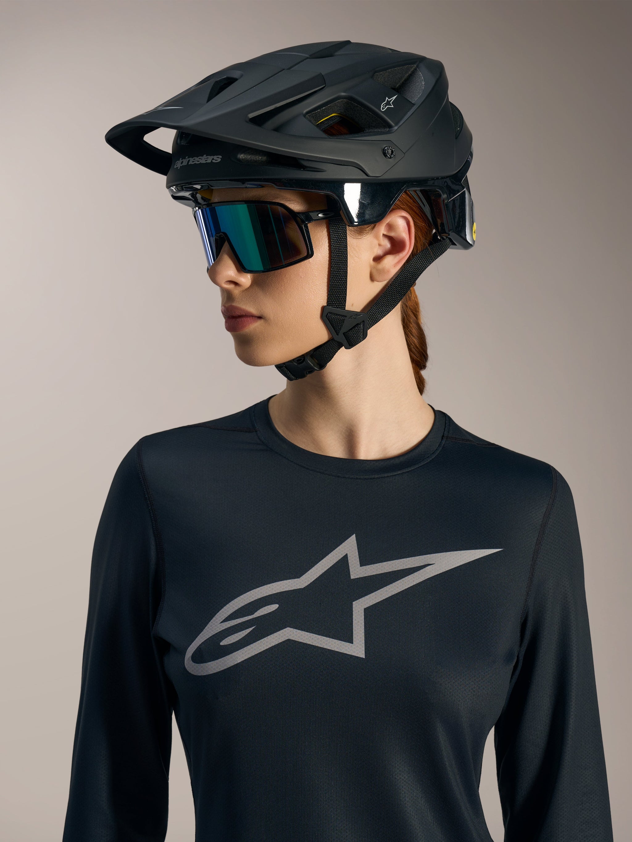 Black Women's Stella A-Dura Ride LS Jersey with grey Astars chest logo, worn with a matte black MTB helmet.