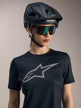 Women Stella A-Dura Ride Short Sleeve Jersey in black, with a large grey chest logo, worn with MTB helmet and sunglasses.