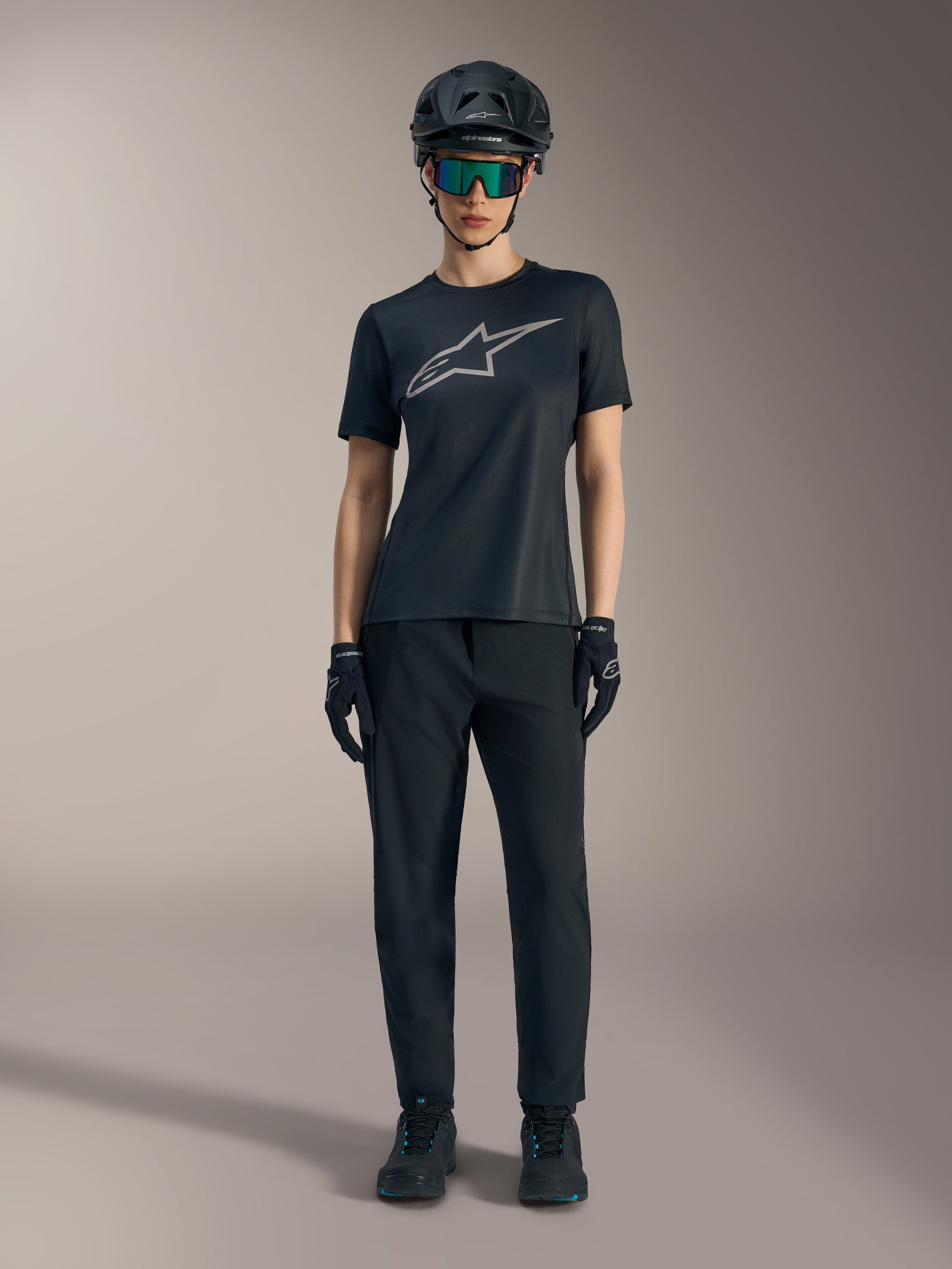 Women's Stella A-Dura Ride SS Jersey in black with silver logo, styled with MTB pants and helmet for off-road riding.