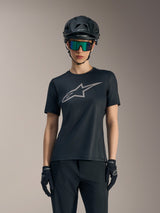Black Women's Stella A-Dura Ride Jersey featuring a grey chest logo, styled with a mountain bike helmet and goggles.