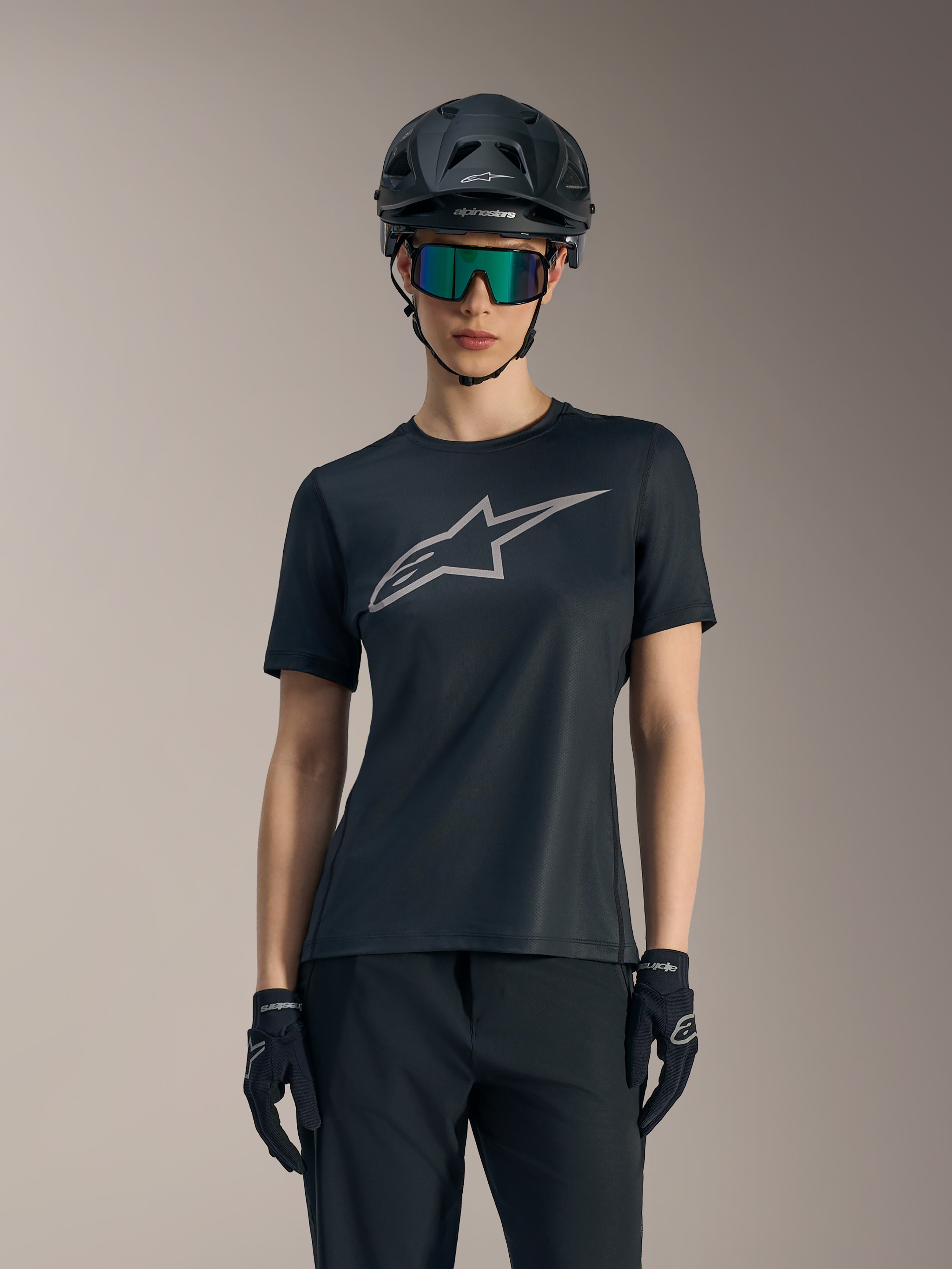 Black Women's Stella A-Dura Ride Jersey featuring a grey chest logo, styled with a mountain bike helmet and goggles.
