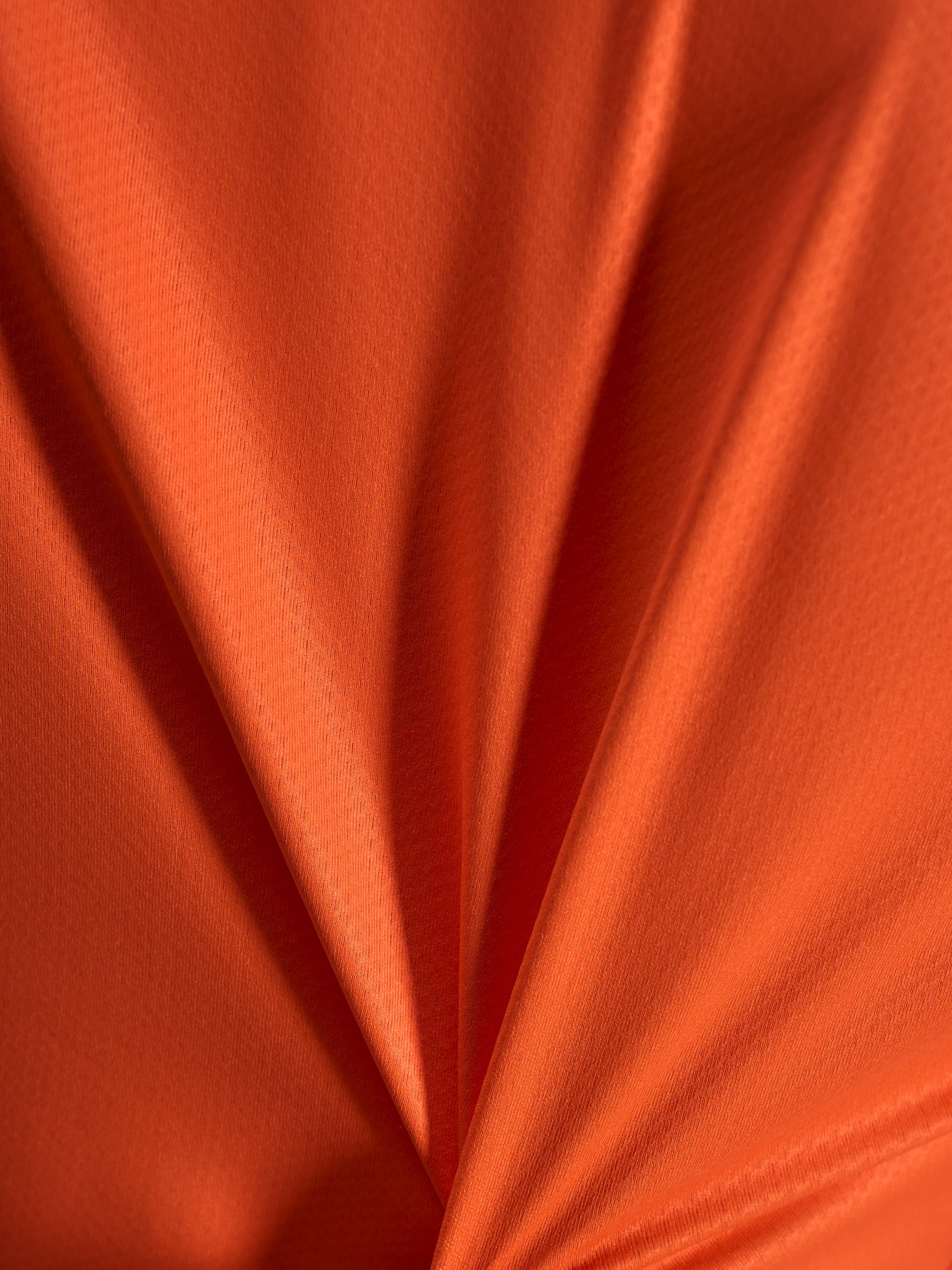 Orange jacquard fabric detail of the Alpinestars Stella A-Dura Ride Jersey, showing its lightweight and stretchy texture.