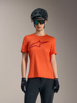 Orange Women's Stella A-Dura Ride short sleeve jersey with red logo, styled with black MTB helmet and sunglasses.