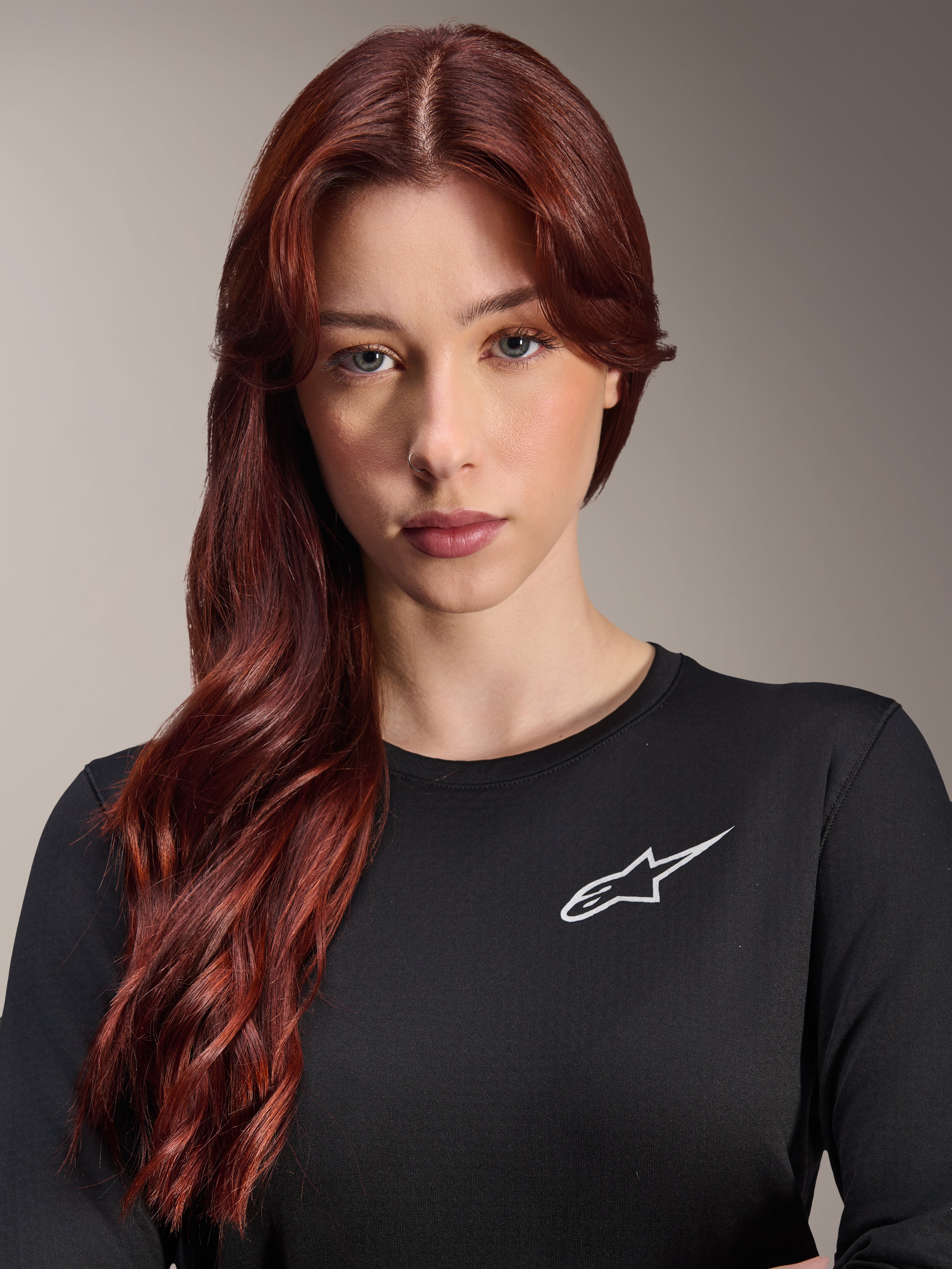 Alpinestars Stella A-Dura Thermal Jersey, Women's Long-Sleeve MTB Jersey, Black with white A-star logo on the chest, close-up portrait of a woman with long red hair, cycling apparel for cool weather.