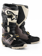 Alpinestars 2026 Tech 7 Enduro Drystar® Boots, Motocross and Enduro Boots, Black Dark Gray and Gold, featuring a rugged TPU shell, quick-release aluminum buckles with gold accents, and a large white shin plate with a black logo, designed for off-road durability.
