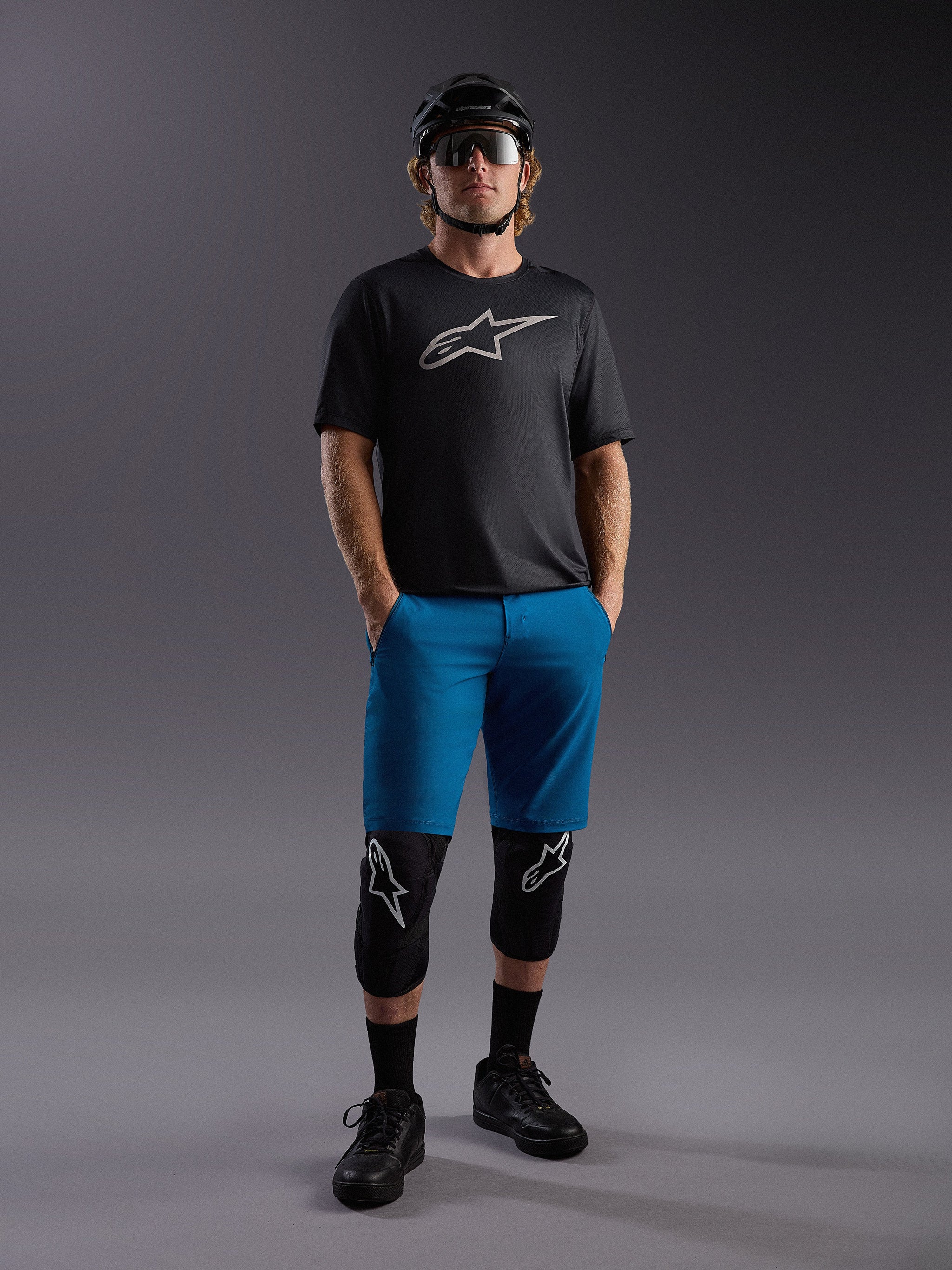 Alpinestars A-Dura Ride SS Jersey and blue shorts, complete mountain bike outfit with protective pads and helmet.