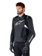 Man wearing the Alpinestars Missile V3 Airflow Leather Jacket, Black and White motorcycle jacket, premium perforated leather for airflow, white Alpinestars logo on chest and sleeve, racing-inspired sport fit, worn with black gloves and pants.