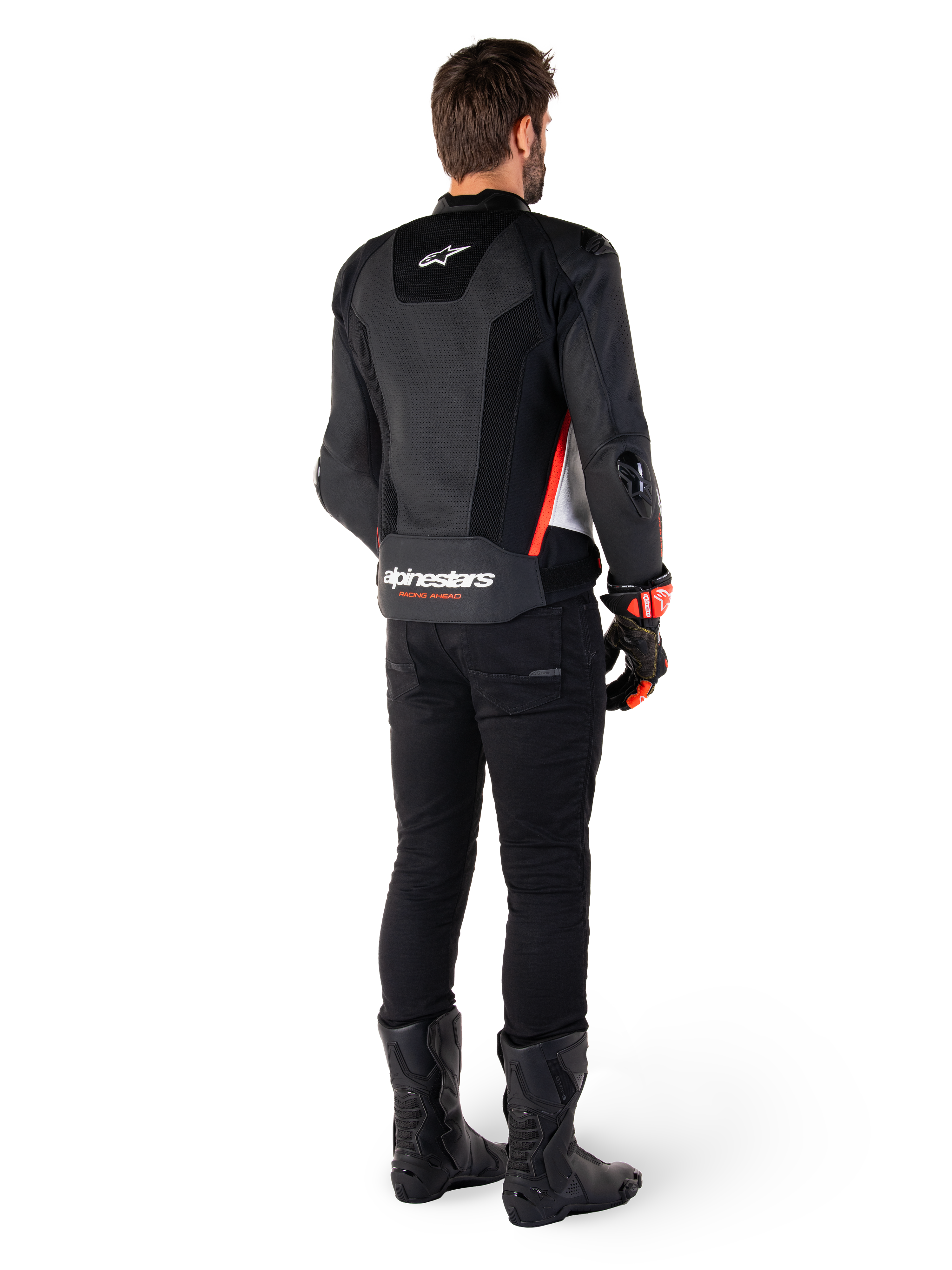 Rider viewed from the back wearing the Alpinestars Missile V3 Airflow Leather Jacket in Black White Red Fluo, styled with black pants and black boots, featuring extensive perforated leather for ventilation, DFS shoulder armor, and prominent Alpinestars branding on the lower back.