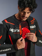 Alpinestars GP Force V2 Air Leather Jacket in Black and Red Fluo, man unzipping the jacket to reveal a red chest protector being inserted, featuring perforated leather, bold white branding, and Tech-Air Ready detail on the internal flap