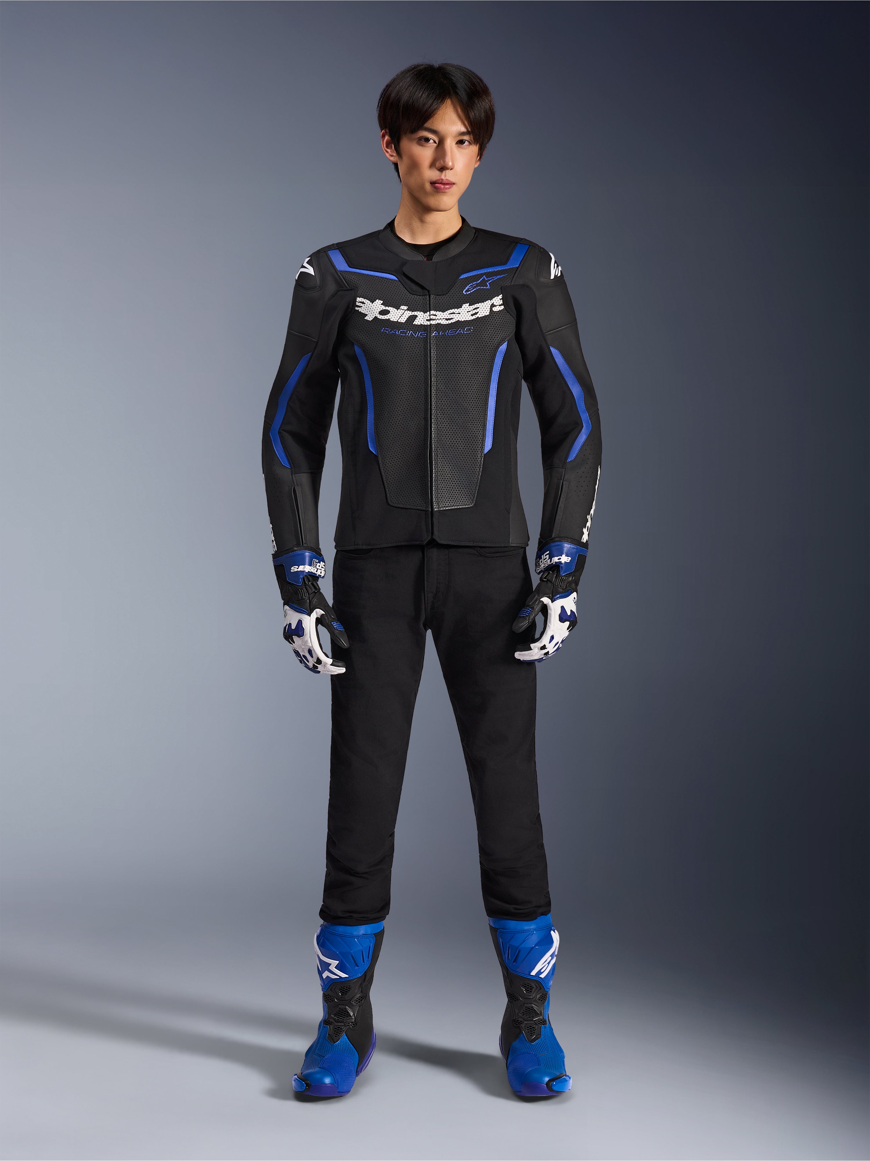 Alpinestars GP Force V2 Airflow Leather Jacket in Black Metallic Blue, worn with matching racing gloves, black pants, and blue boots, professional sport motorcycle riding gear, full-body studio shot