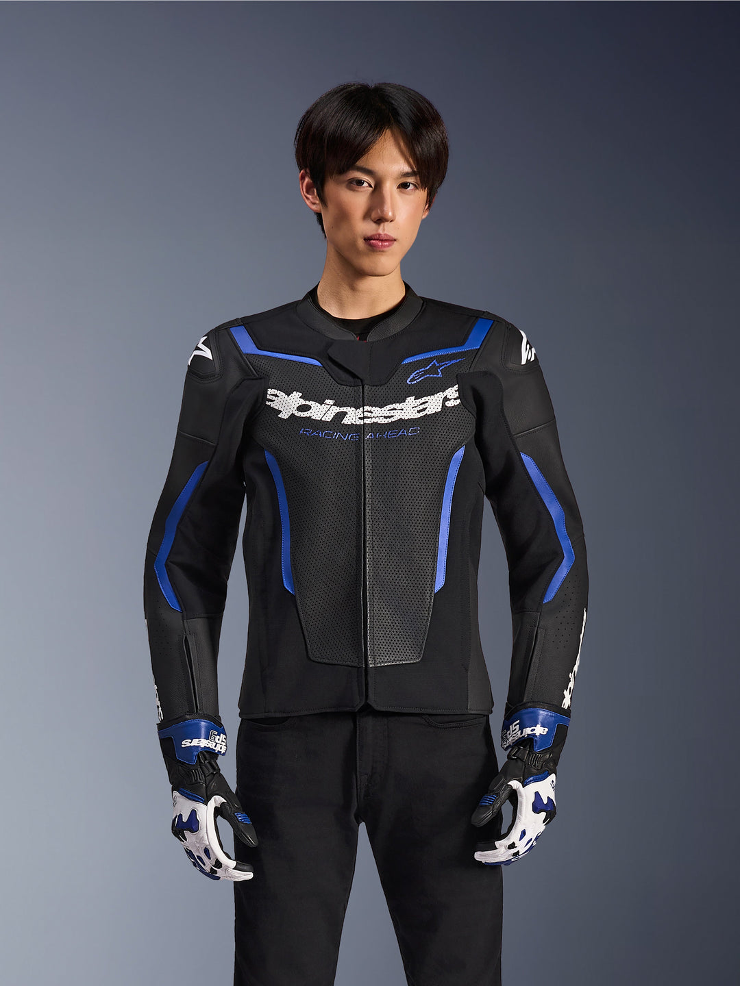 Alpinestars GP Force V2 Airflow Leather Jacket, Black Metallic Blue, motorcycle jacket with perforated leather and blue accents, worn by a model with matching racing gloves and black pants, professional sport riding gear