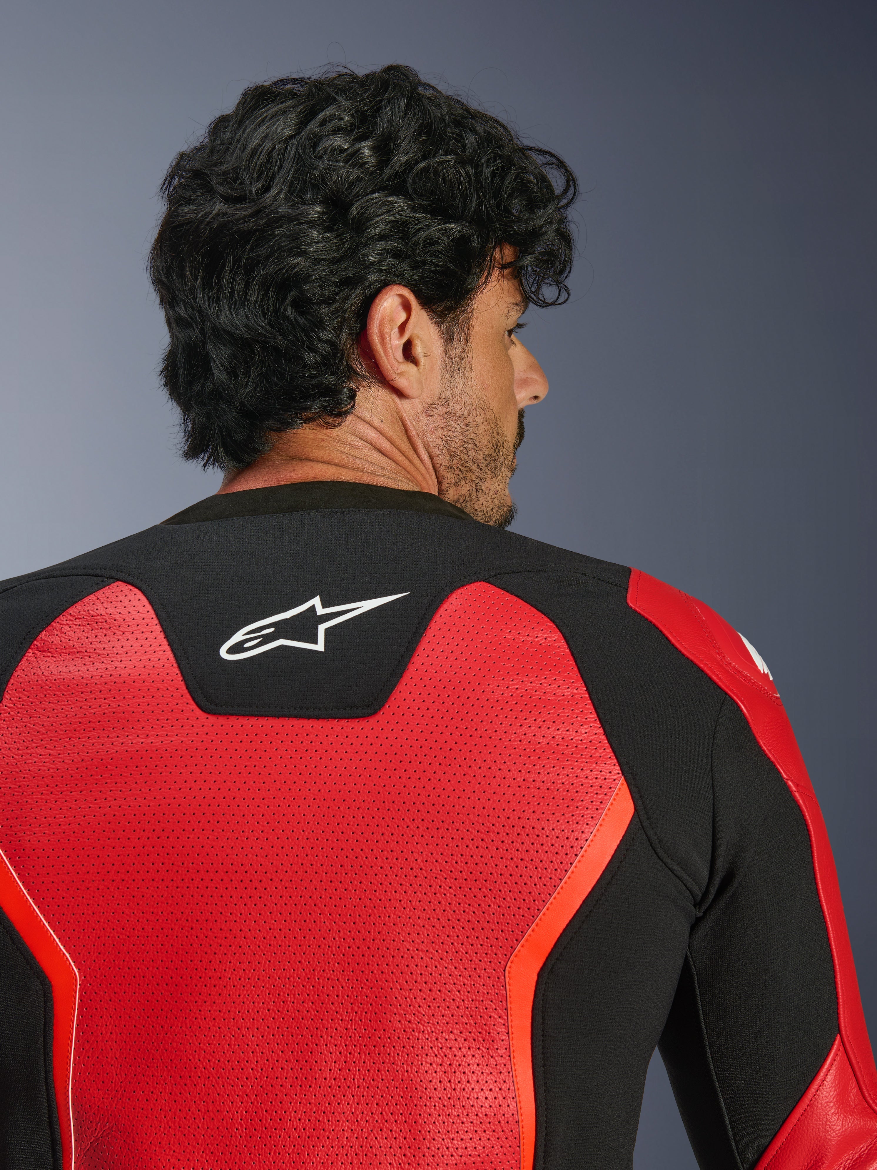 Alpinestars GP Force V2 Air Leather Jacket, Red and Black, close-up back view featuring extensive perforated leather for airflow, black stretch panel with white Astars logo, sport-fit motorcycle riding jacket