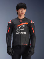 Alpinestars GP Plus R V4 Airflow Leather Jacket in Black with Red Fluo and White accents, worn by a model, featuring perforated leather construction, a large white ASTARS logo on the chest, and integrated shoulder armor for motorcycle racing.