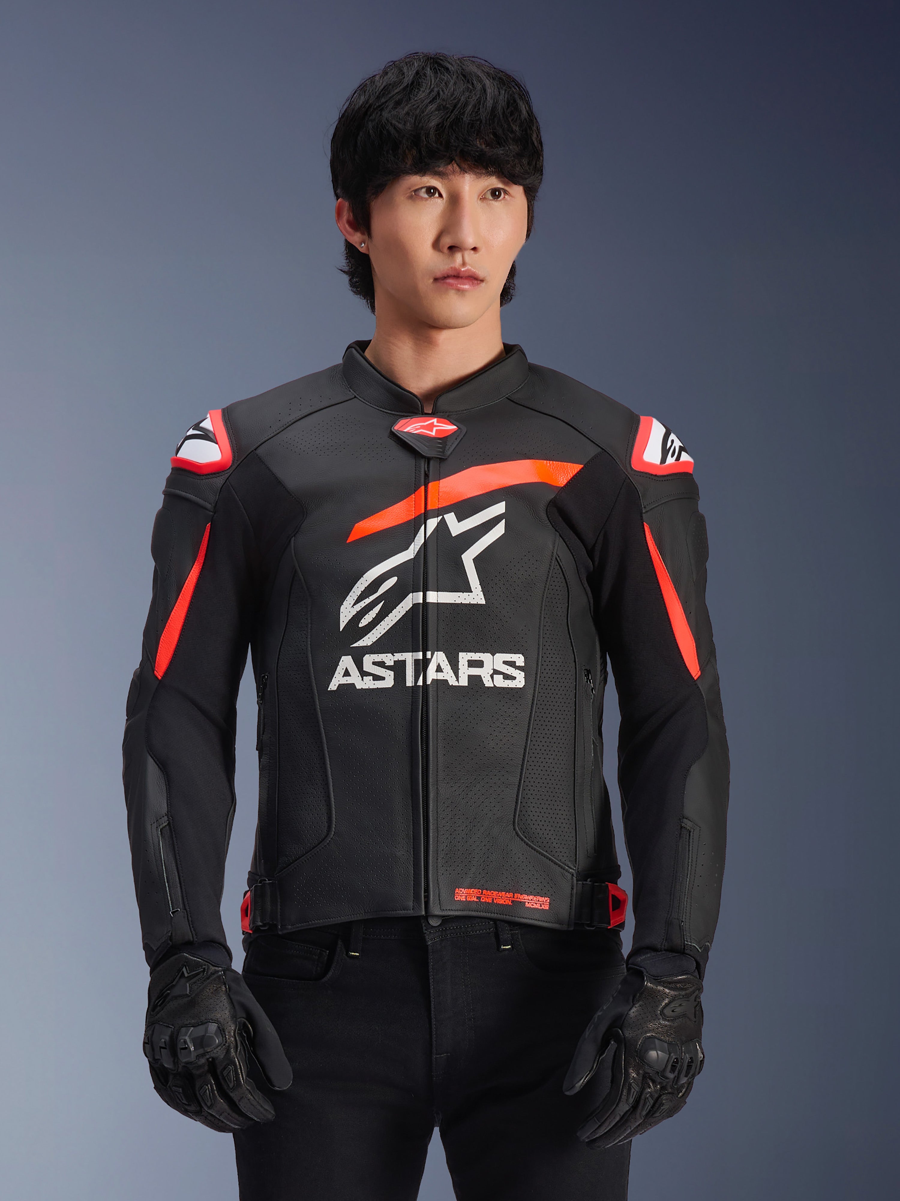 Alpinestars GP Plus R V4 Airflow Leather Jacket in Black with Red Fluo and White accents, worn by a model, featuring perforated leather construction, a large white ASTARS logo on the chest, and integrated shoulder armor for motorcycle racing.