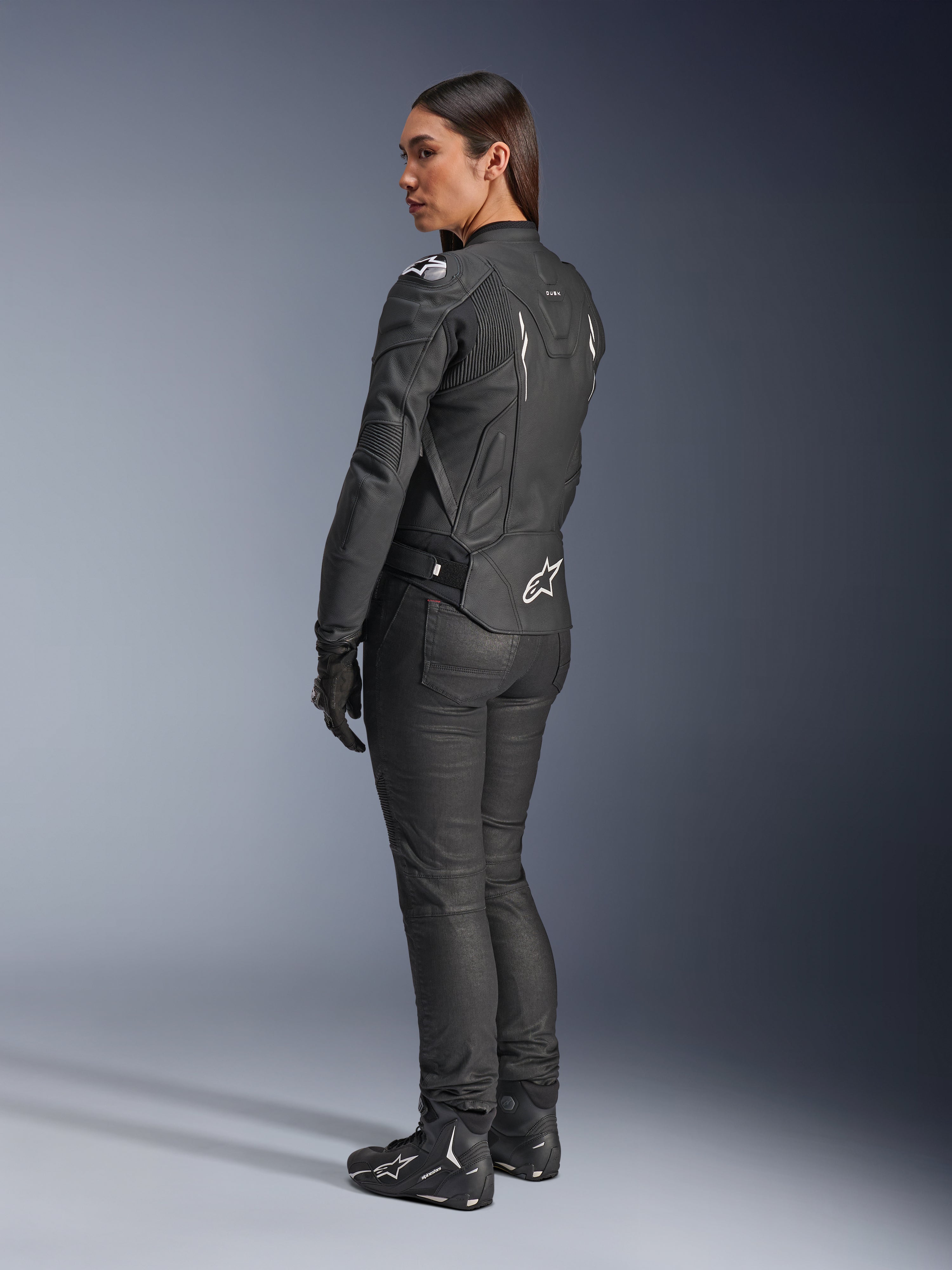 Alpinestars Stella Dusk Leather Jacket, Women's Motorcycle Jacket, Black and White, rear view featuring white Alpinestars logo on the lower back and shoulders, worn with black riding pants and boots, sport-focused ergonomic fit for road riding
