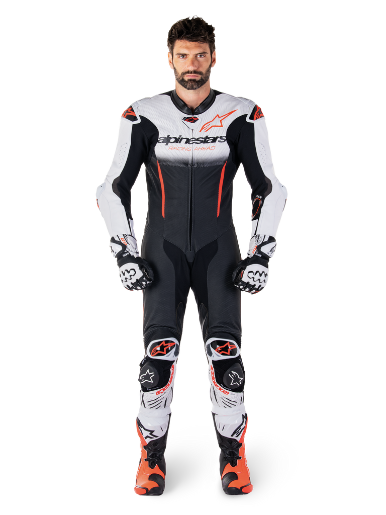 Male rider wearing the Alpinestars GP-R7 One Piece Leather Suit in White Black and Red Fluo, coordinated with matching racing gloves and boots, professional motorcycle track gear featuring a streamlined race fit and bold branding