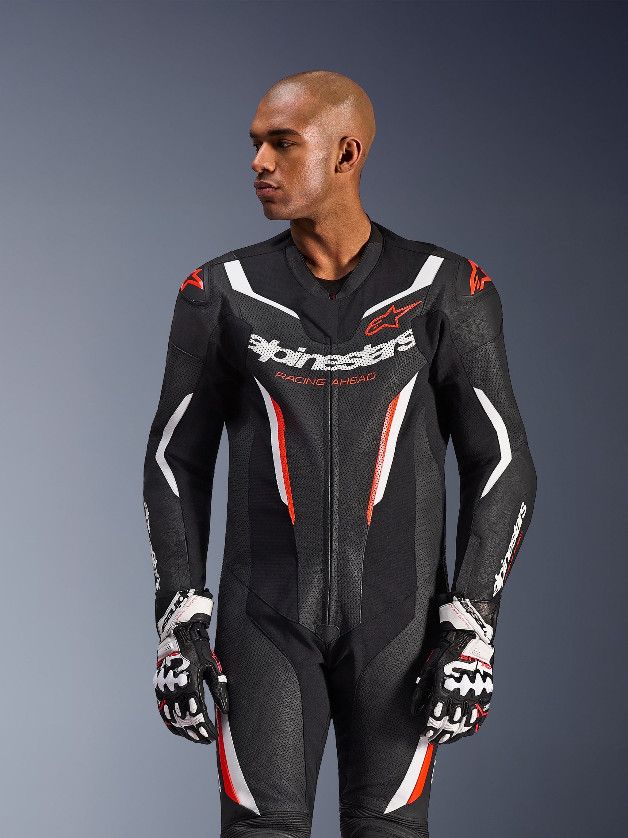 Alpinestars GP Force V2 Leather Suit - 1Piece, Motorcycle Racing Suit, Black White and Red Fluo, featuring perforated leather panels, bold chest branding with 'Racing Ahead' text, and ergonomic protective design, worn with matching racing gloves