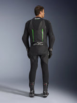 Rear view of the Alpinestars GP Force V2 1-Piece Leather Suit in Black and Green, featuring an aerodynamic speed hump, perforated panels, and Tech-Air Ready branding on the lower back, worn with black racing gloves and boots.