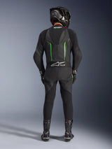 Rider from the back wearing Alpinestars GP Force V2 Leather Suit - 1Piece in Black and Green, paired with a black carbon fiber helmet, black racing gloves, and black boots, featuring an aerodynamic speed hump and Tech-Air Ready branding.