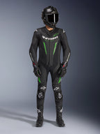 Motorcycle racer wearing Alpinestars GP Force V2 Leather Suit - 1Piece in Black and Green, paired with a carbon fiber helmet and racing gloves, featuring perforated leather panels and white Alpinestars logos, professional track and sport riding gear