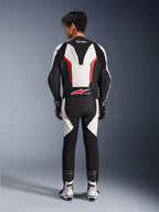 Alpinestars GP Force V2 Leather Suit 1-Piece, Motorcycle Race Suit, White Black and Red Fluo, back view of model wearing the suit with racing boots and gloves, featuring an aerodynamic speed hump, accordion stretch panels, and Tech-Air Ready branding
