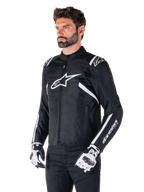 Alpinestars T-SPS V2 Waterproof Jacket, Black and White, worn by male model with matching motorcycle gloves, sport-cut textile jacket with white Alpinestars logos on chest and shoulders, 'alpinestars T-SPS' branding on sleeve, sleek race-inspired motorcycle gear