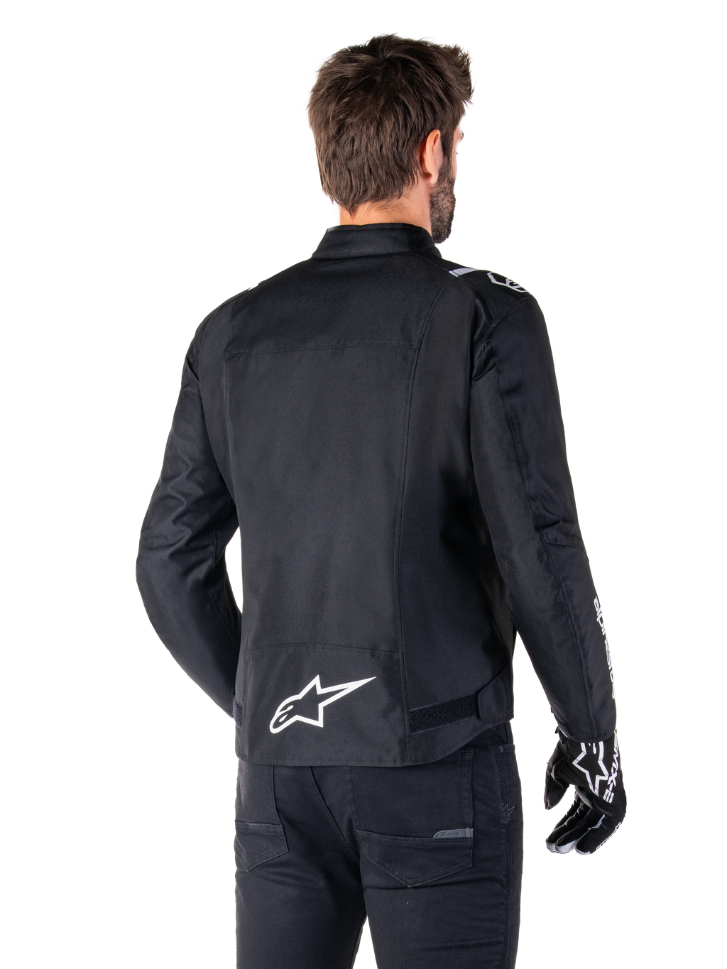 Alpinestars T-SPS V2 Waterproof Jacket, Black and White, rear view of a male rider wearing the jacket, white Alpinestars logo on the lower back, sport cut textile construction, worn with black riding pants and gloves