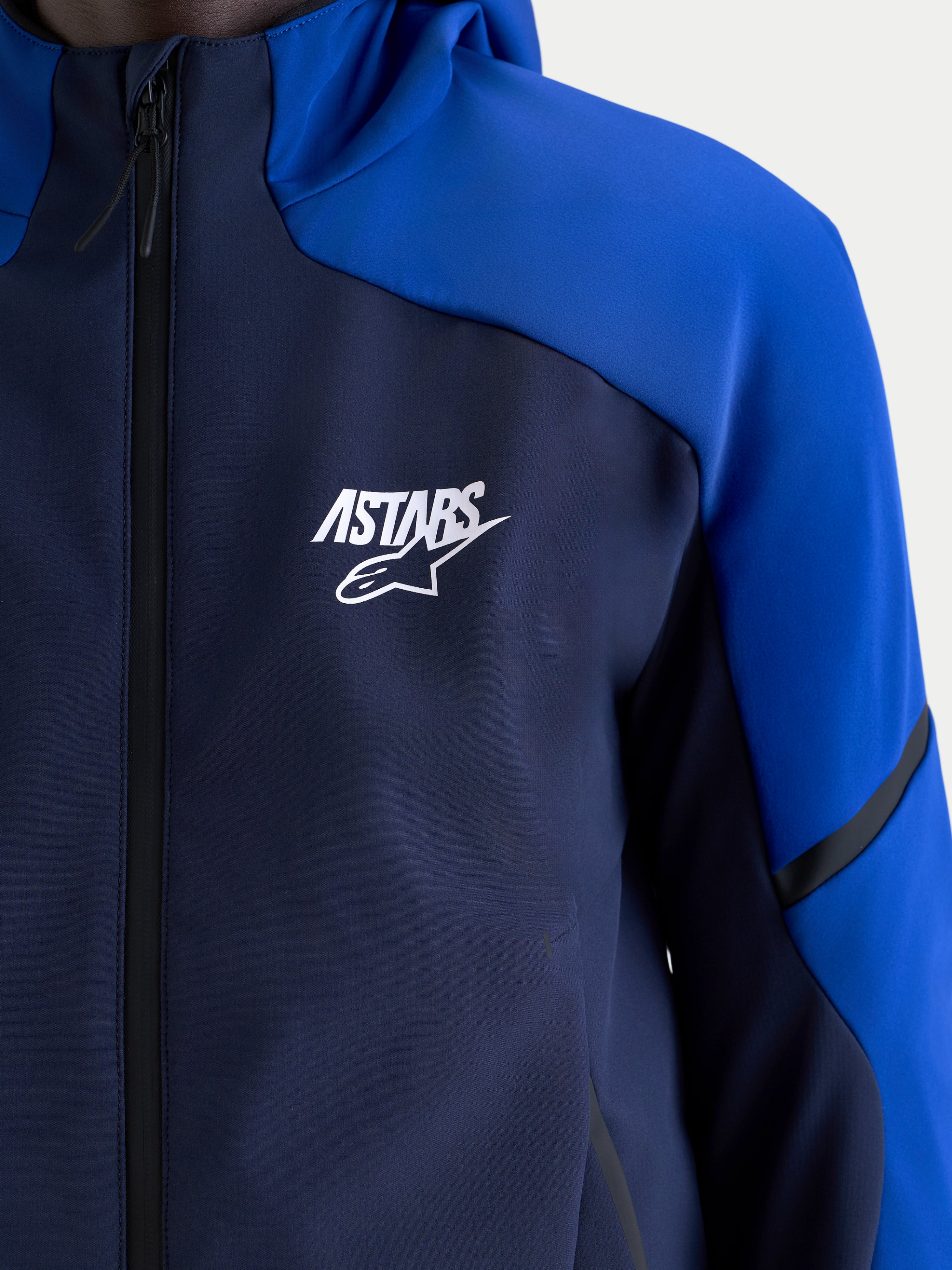 Alpinestars Aeroshell Waterproof Jacket, Night Navy and Bright Blue, close-up view of a men's textile motorcycle sports softshell featuring a white Astars logo on the chest, waterproof zipper, and hood