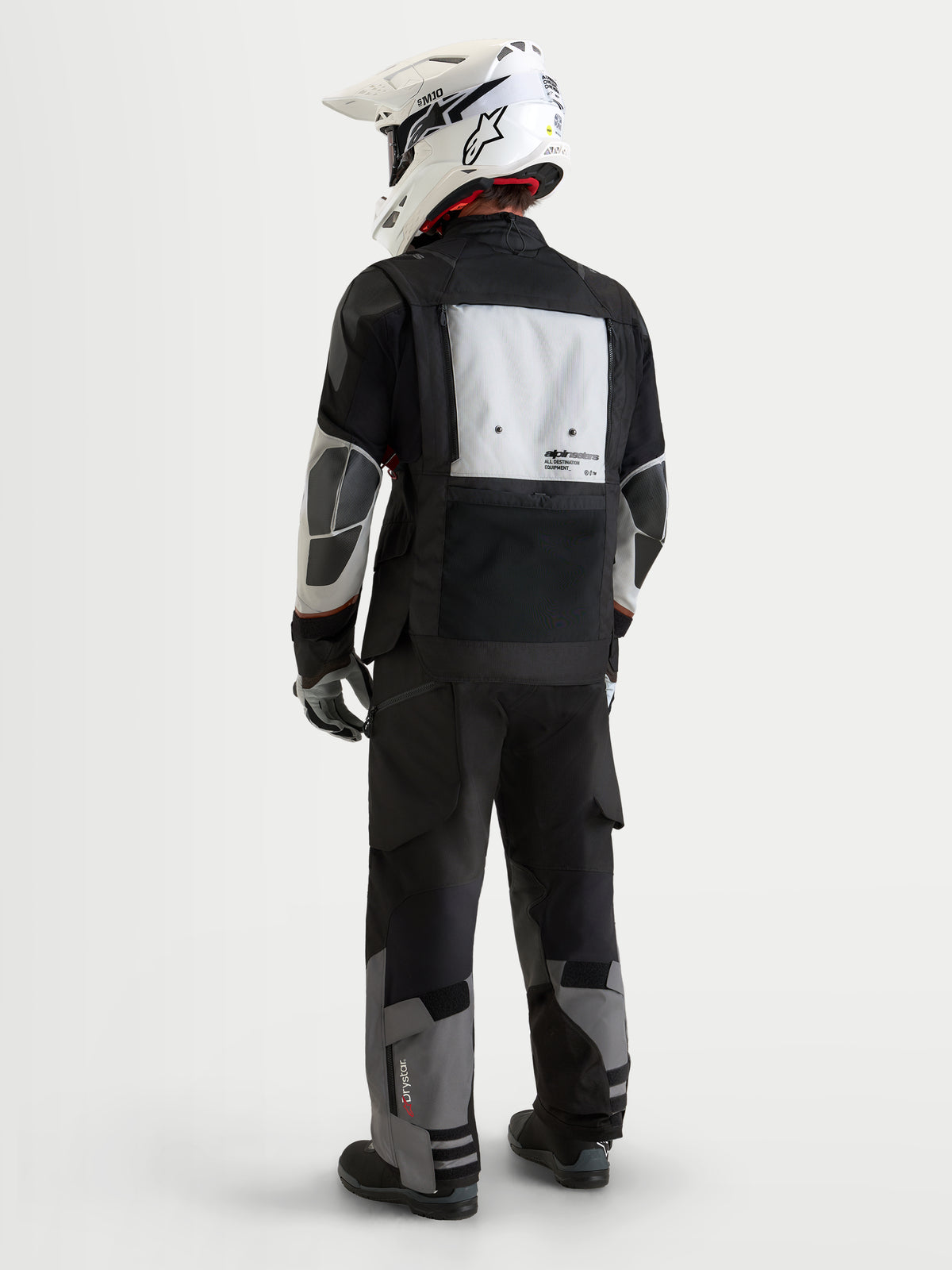 Alpinestars Harok V2 Drystar Jacket, Men's adventure motorcycle jacket, Dark Gray, Ice Gray and Black, rear view showing modular ventilation panel, PU reinforcement zones, and matching adventure pants with a white off-road helmet