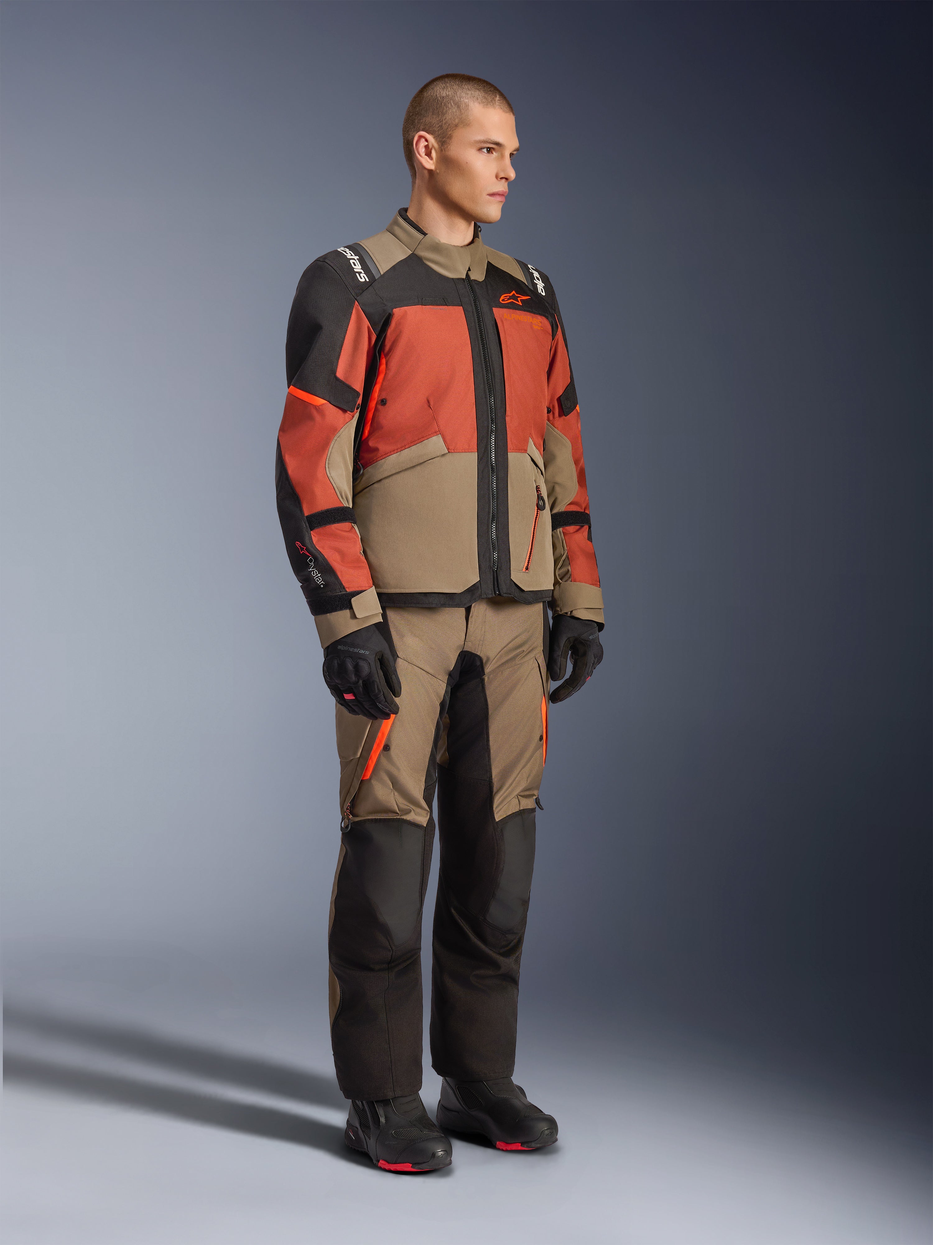 Alpinestars Andes V4 Drystar® Jacket, Adventure Touring Jacket, Walnut Rust Black, worn with matching pants and black boots, featuring a color-blocked design in tan, rust, and black, durable textile construction with visible zippers and Alpinestars logos.