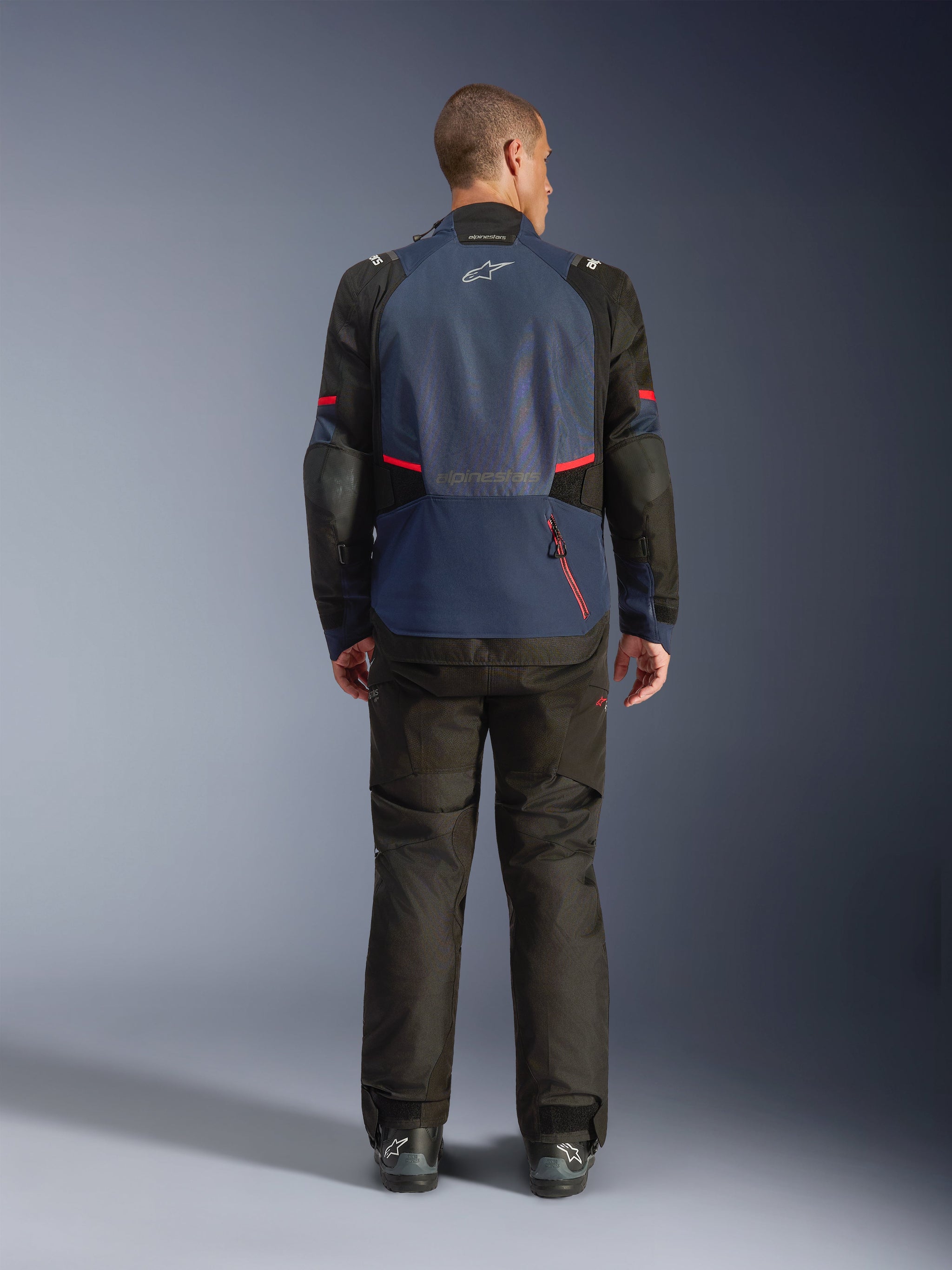 Alpinestars Andes V4 Drystar® Jacket, Back view, Night Navy and Mood Indigo with black panels and red accents, worn with matching black trousers, featuring Alpinestars logo on the upper back and a large rear compartment zipper.