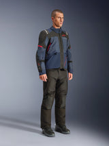 Male model wearing Alpinestars Andes V4 Drystar® Jacket in Night Navy and Mood Indigo with black panels and red accents, paired with black motorcycle pants and boots, technical adventure touring gear in a studio setting.