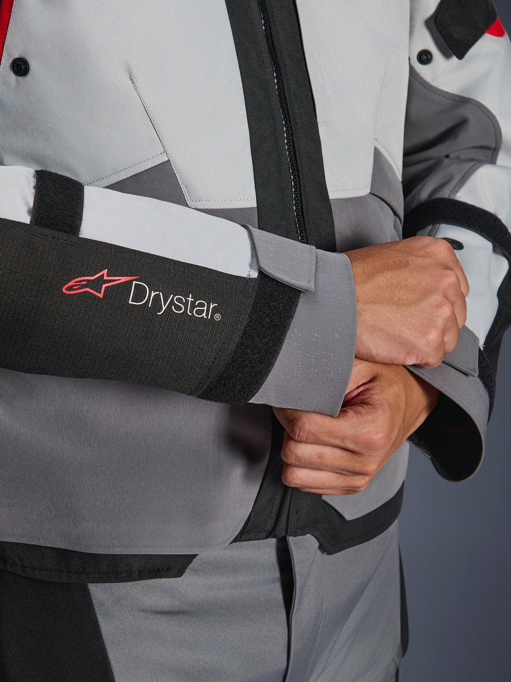 Close-up detail of Alpinestars Andes V4 Drystar® Jacket sleeve, Gray and Black textile, featuring red and white Drystar logo on forearm, adjustable velcro wrist closure, high-performance waterproof motorcycle gear