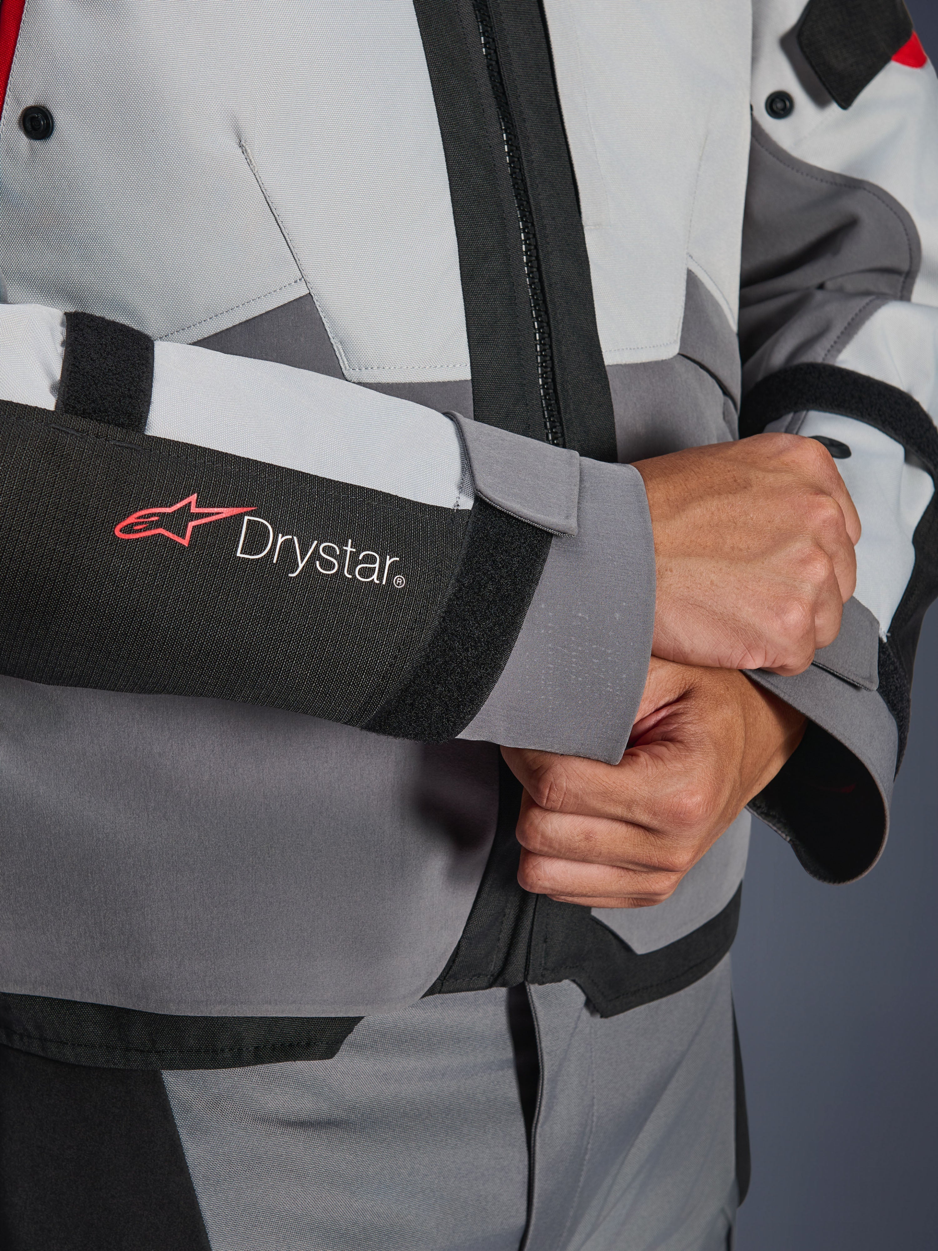Close-up detail of Alpinestars Andes V4 Drystar® Jacket sleeve, Gray and Black textile, featuring red and white Drystar logo on forearm, adjustable velcro wrist closure, high-performance waterproof motorcycle gear