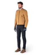 Male rider wearing the Alpinestars Clayton WR Jacket in Utility Brown Light Gold, urban contemporary motorcycle jacket with quilted shoulder details, styled with black pants, black gloves, and brown boots