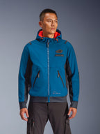 Alpinestars Moblast Waterproof Jacket worn by model, Blue and Dark Navy, Motorcycle Urban Riding Jacket, Hooded design with red interior lining, Black zippers and chest patch detail, Streetwear-inspired motorcycle gear