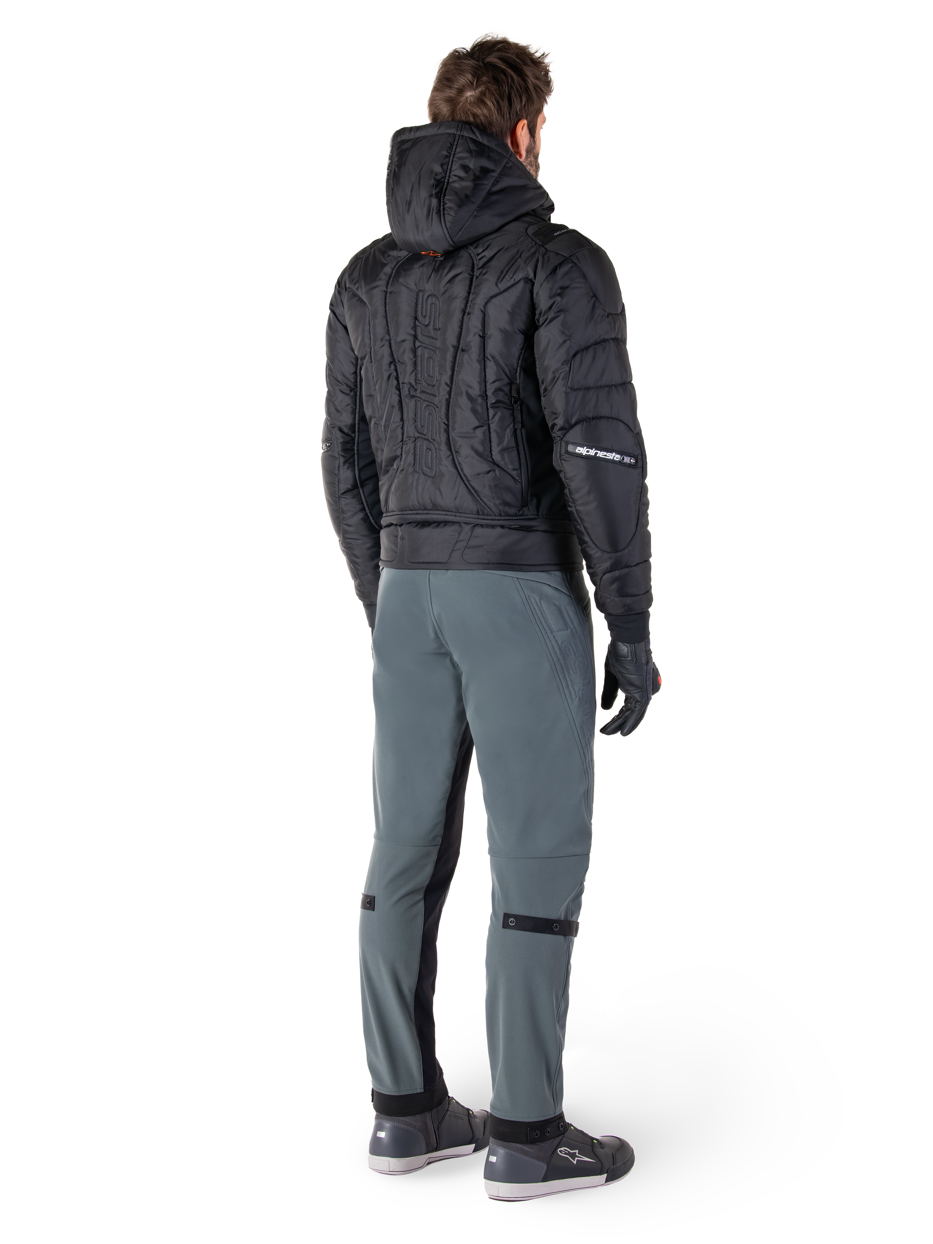 Alpinestars Mohobbs Waterproof Jacket, Black, Rear view of quilted padded bomber jacket with embossed vertical wordmark on the back, styled with grey riding pants and black gloves, urban streetwear-inspired motorcycle gear