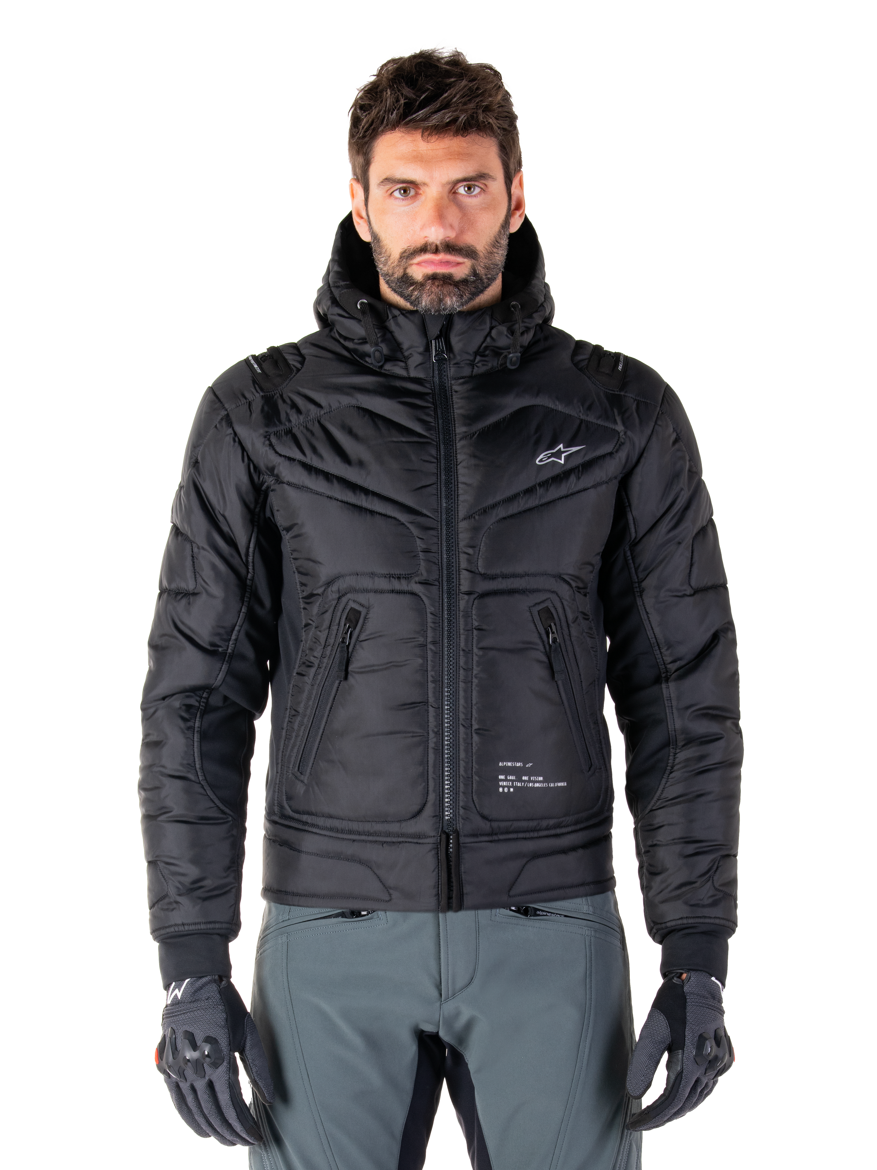 Alpinestars Mohobbs Waterproof Jacket, Black Padded Bomber Motorcycle Jacket, quilted poly fabric with front zipper and zippered pockets, small white logo on chest, worn by a model with grey pants and gloves, urban streetwear design for city riding.