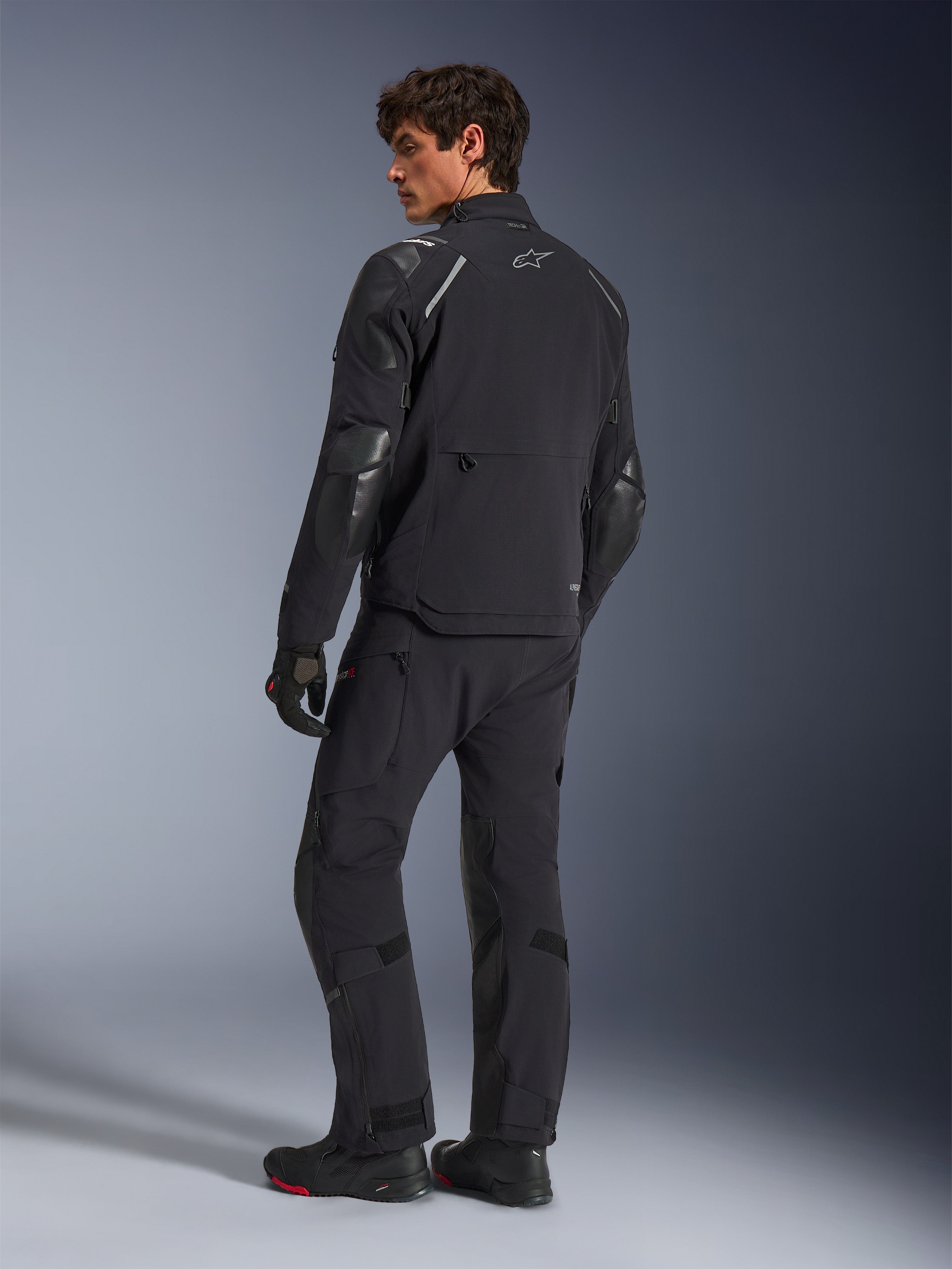 Alpinestars Andes Pro Drystar® XF Jacket, Adventure Motorcycle Jacket, Black, back view worn with matching pants and boots, featuring reinforced panels and silver star logo, technical all-weather riding gear