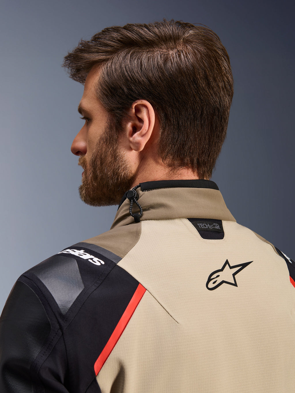 Alpinestars Andes Pro Drystar® XF Jacket in Walnut Aluminum, close-up back view showing the collar and upper shoulders, featuring the Alpinestars logo, Tech-Air compatibility branding, red accents, and a shock cord adjustment system on the neck.