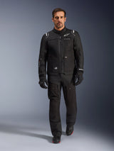 Male rider wearing the Alpinestars Cusco Drystar® Jacket in Black, paired with matching black technical riding pants and gloves, studio full-body shot, adventure touring motorcycle gear with visible Alpinestars branding and multi-pocket design