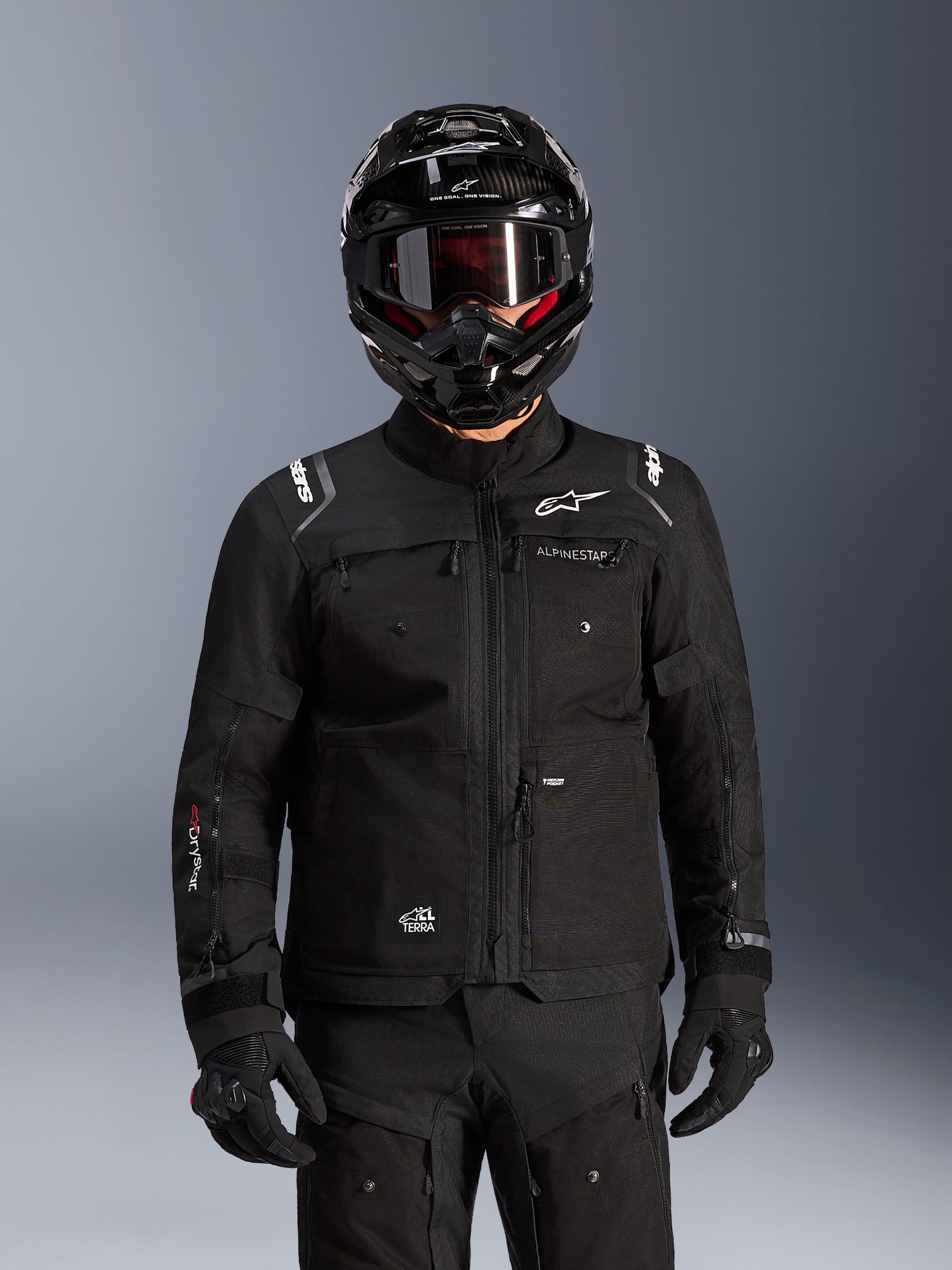 Alpinestars Cusco Drystar® Jacket, Black motorcycle adventure touring jacket, worn with a black full-face adventure helmet and dark goggles, featuring multiple utility pockets, Alpinestars branding on the chest, and Drystar® logo on the sleeve, part of a complete road adventure outfit.