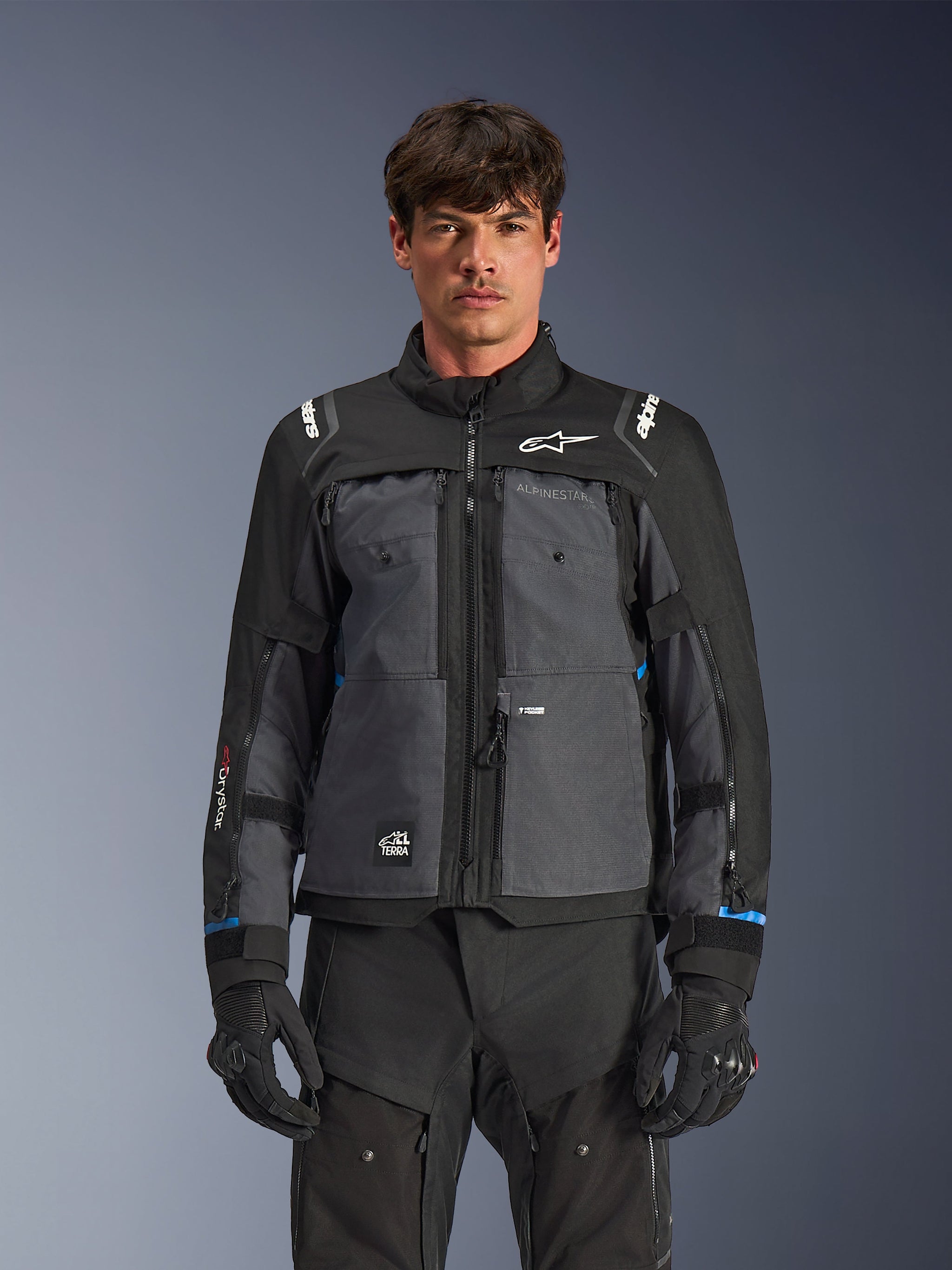Alpinestars Cusco Drystar® Jacket, Motorcycle Touring Jacket, Black and Deep Gray, front view on model, featuring Alpinestars logos on chest and shoulders, Drystar® sleeve branding, technical multi-pocket design with ventilation zippers, paired with black riding gear