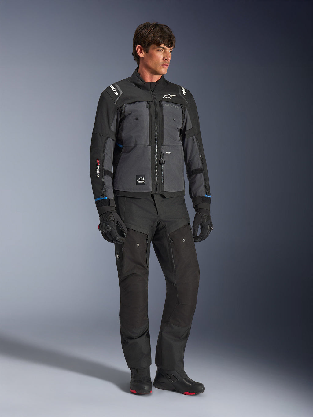 Alpinestars Cusco Drystar® Jacket in Black and Deep Gray, technical motorcycle touring jacket with multi-tonal panels, worn with matching black riding pants and gloves, designed for road and adventure touring.