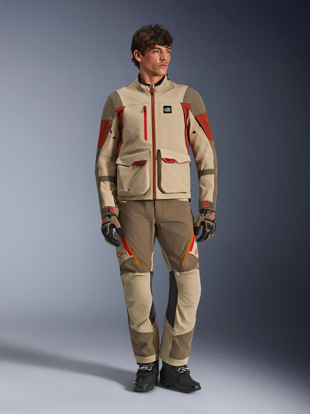 Maxdura Drystar®XF Laminated Armored Shell, adventure motorcycle jacket in Aluminum Walnut Rust Brown, worn by a male model with matching adventure pants, gloves, and boots, full-body studio shot of professional touring gear.