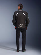 Alpinestars T-GP R V3 Drystar® Jacket, Black and White, rear view, waterproof textile motorcycle jacket featuring a large white star logo on the lower back and white accents on the shoulders, paired with black pants and boots, race-derived sport design